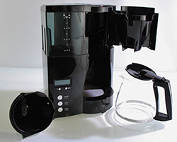 Auf dem Bild ist die Melitta 100801 Optima Timer Kaffeemaschine zu sehen. Mit einer Glaskanne und einem herausnehmbaren Filterkorb. Was die Reinigung deutlich vereinfacht.